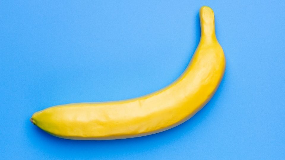 Gelbe Banane auf blauem Hintergrund: ein minimalistisches Design, das als Hinweis auf Kunst und Kreativität dient.